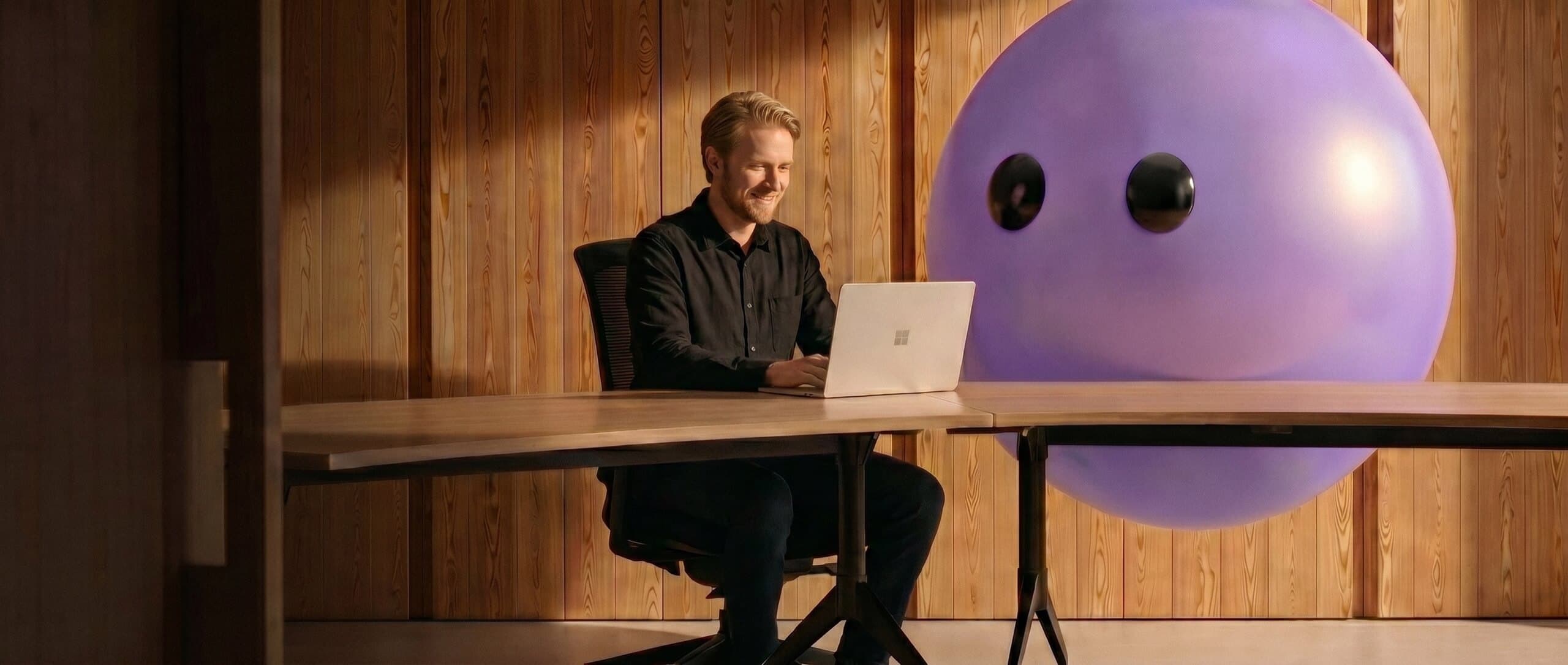 Support agent working at a laptop next to the Lyro mascot