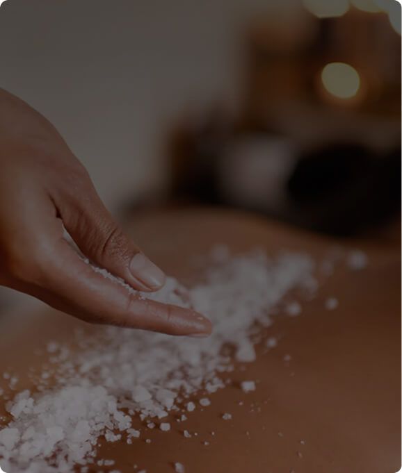 Spa therapist applying an exfoliating salt scrub during a treatment