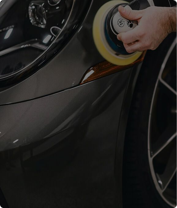 Technician polishing a car headlight during a detailing service